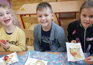 Dzieci z uśmiechem pokazują kanapki.